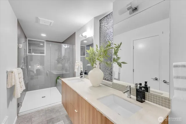 a bathroom with a double vanity sink a toilet and shower