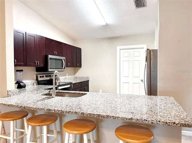 a kitchen with granite countertop a sink a stove and wooden cabinets