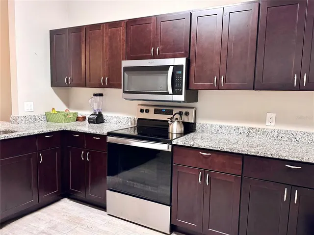 a kitchen with granite countertop wooden cabinets and stainless steel appliances