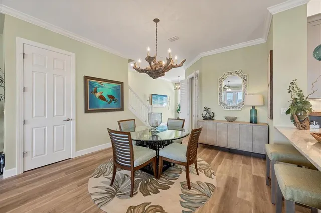 a dining area with furniture a chandelier and wooden floor