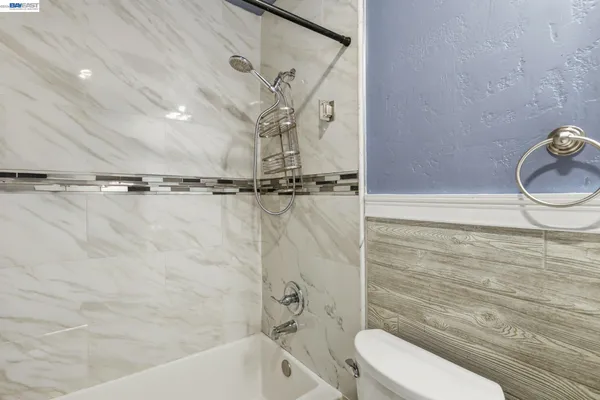 a bathroom with a granite countertop bathtub shower sink vanity and toilet