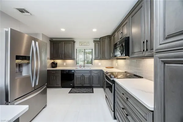 a kitchen with stainless steel appliances granite countertop a refrigerator stove and sink