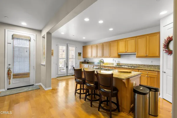 a kitchen with stainless steel appliances granite countertop a stove top oven a refrigerator a sink and a dining table with granite countertops