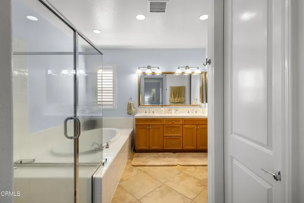 a bathroom with a tub a double vanity sink and mirror