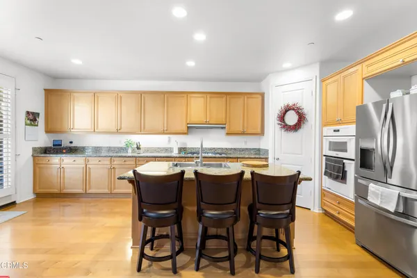 a kitchen with granite countertop white cabinets refrigerator and dining table
