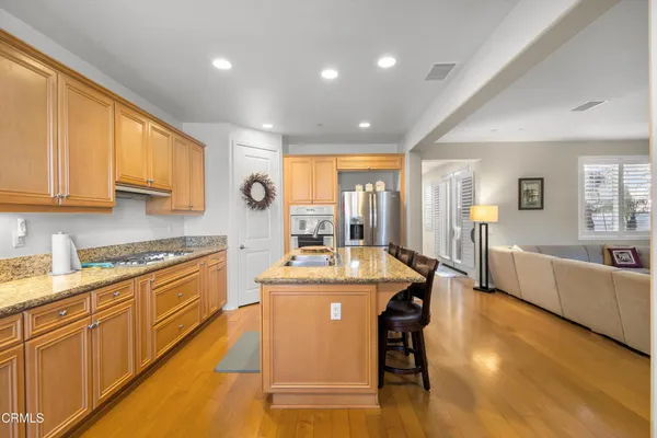 a large kitchen with kitchen island a large counter top space a sink a stove and a refrigerator a window