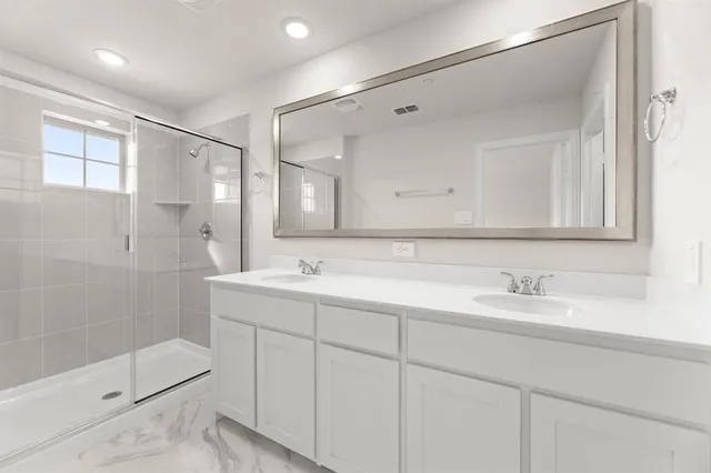 a bathroom with a double vanity sink mirror and shower