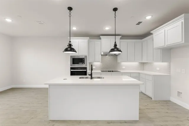 a kitchen with kitchen island a sink stainless steel appliances and white cabinets