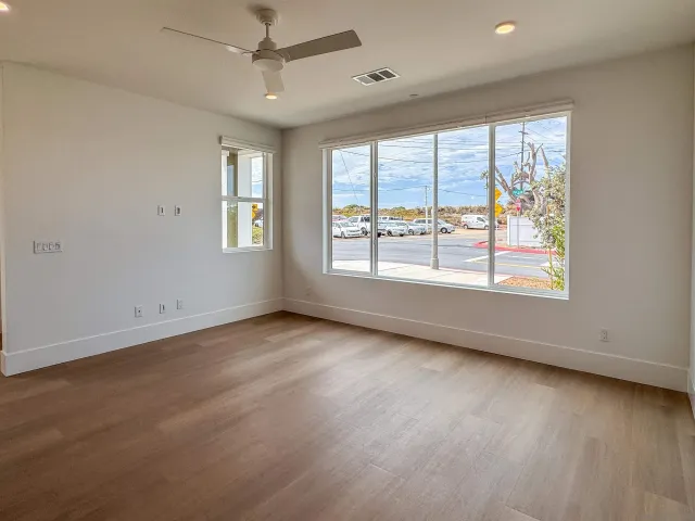 a view of an empty room with a window and wooden floor