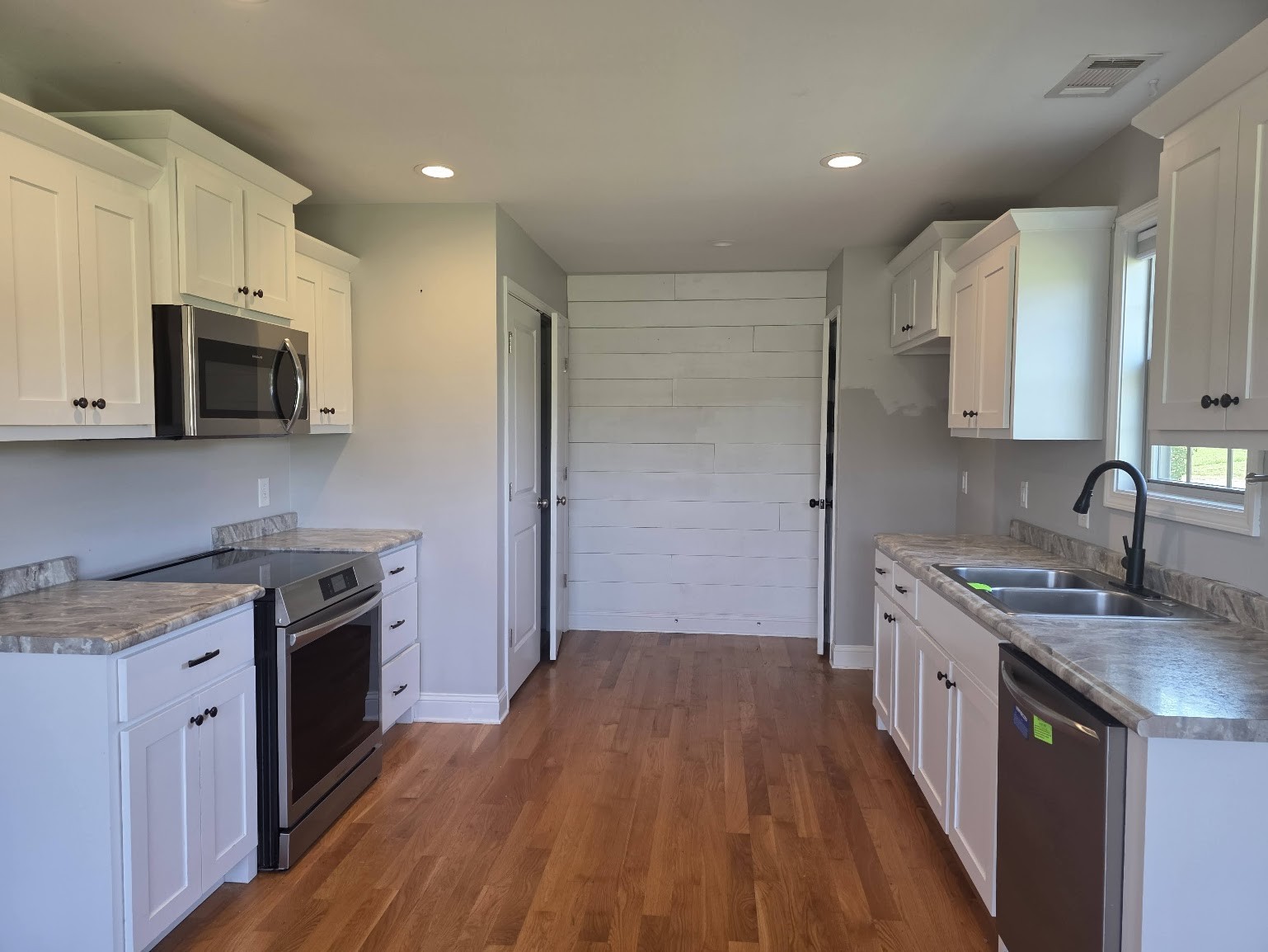 4927 Minnis Road Springfield, TN 37172 - Photo 4 of 15 a kitchen with stainless steel appliances granite countertop a stove top oven a sink dishwasher a refrigerator and a microwave oven with wooden floor
