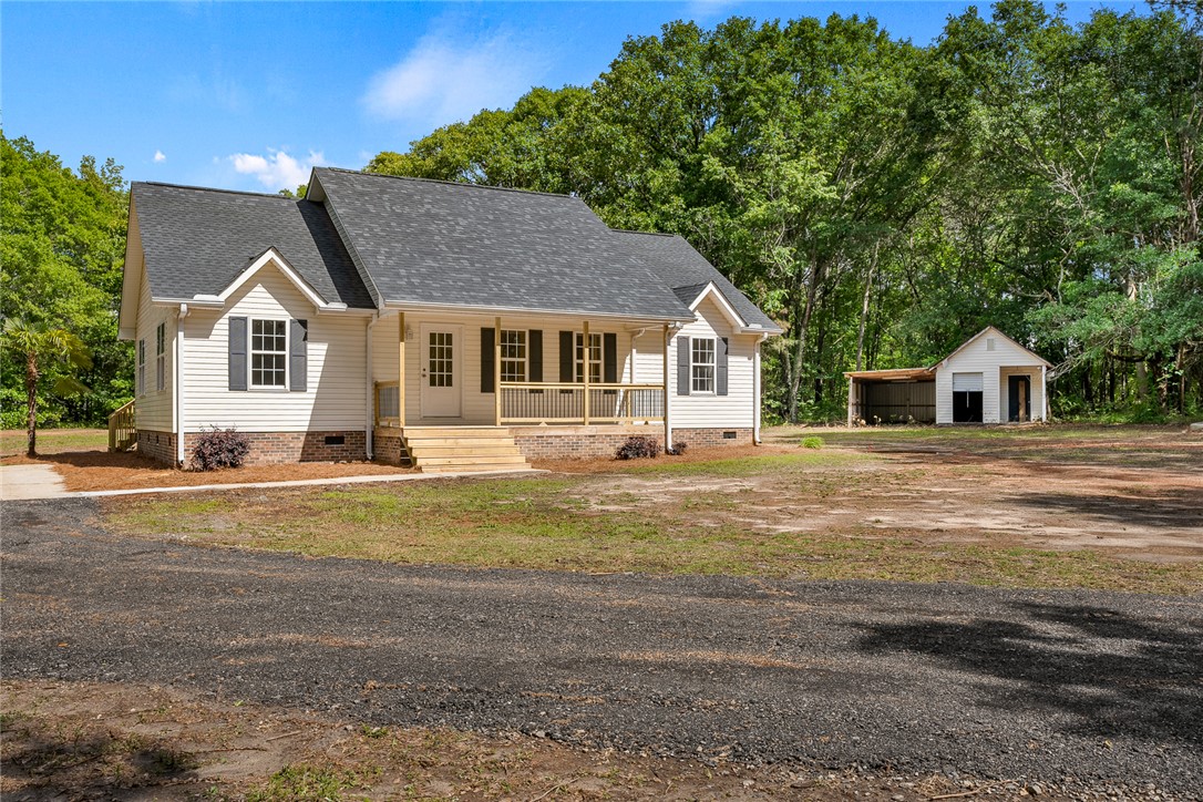 131 Lockaby Road Pelzer, SC 29669 - Photo 8 of 50 This inviting home offers classic appeal with a welcoming front porch, surrounded by lush natural landscaping.