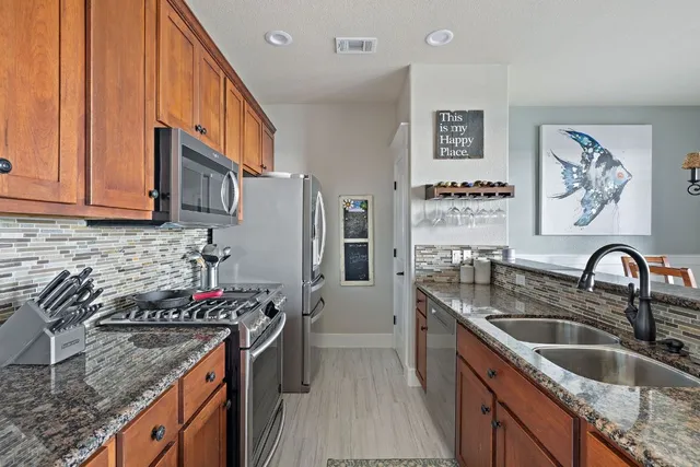 a kitchen with stainless steel appliances granite countertop a sink stove and a refrigerator