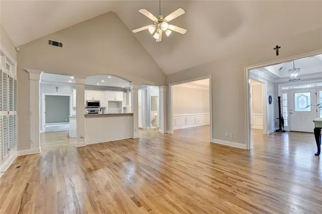an empty room with wooden floor chandelier and a window