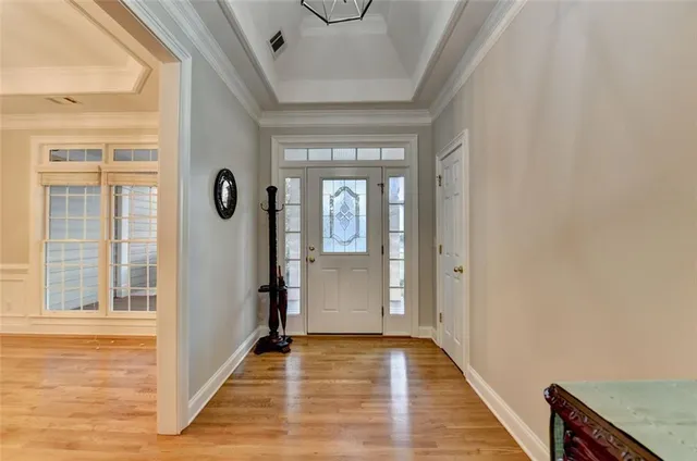 a view of a livingroom with wooden floor a chandelier and windows