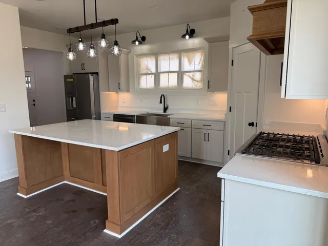 a kitchen with white cabinets a sink dishwasher and a stove with wooden floor