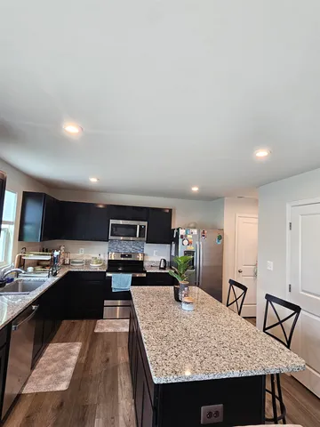 a kitchen with stainless steel appliances granite countertop a sink refrigerator and cabinets