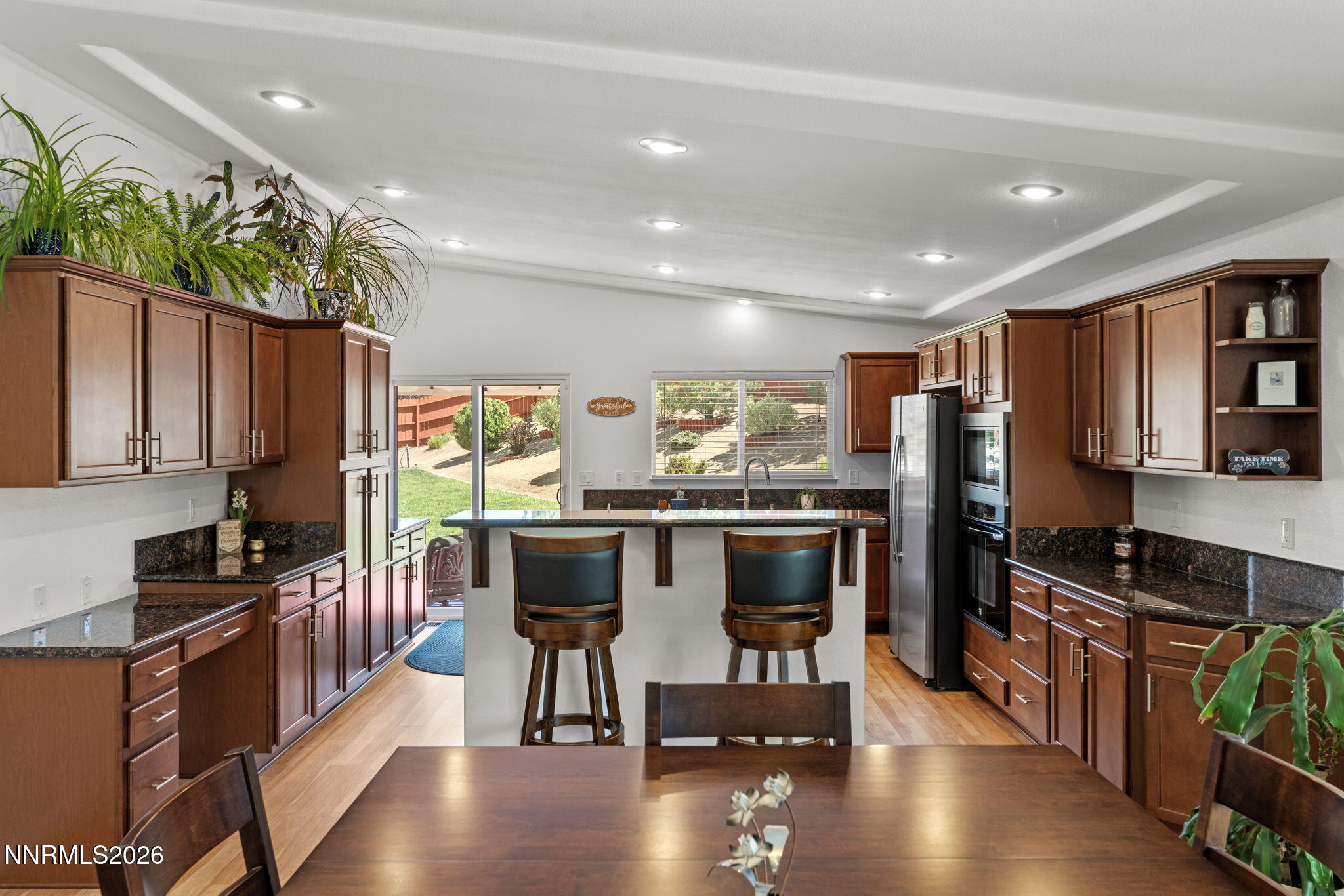 18324 Panda Bear Court Reno, NV 89508 - Photo 6 of 44 a kitchen with stainless steel appliances kitchen island granite countertop a stove refrigerator and a dining table with wooden floor