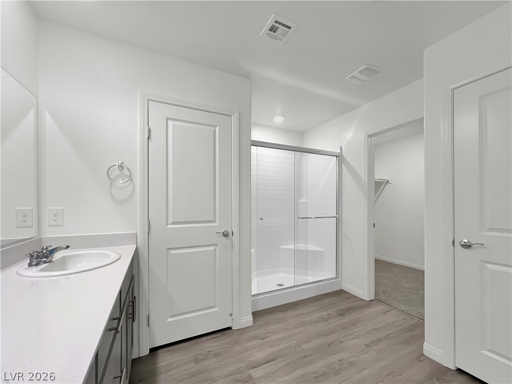 9984 Indigo Cliffs Street Las Vegas, NV 89141 - Photo 17 of 31 Full bathroom featuring visible vents, a stall shower, vanity, and wood finished floors
