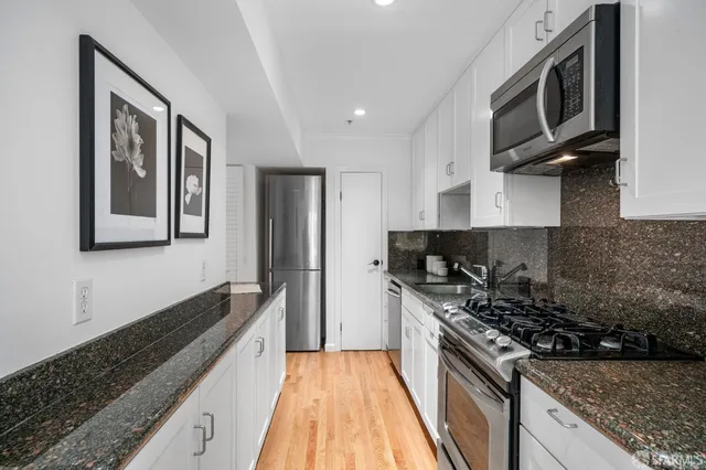 a kitchen with stainless steel appliances granite countertop a sink stove refrigerator and cabinets