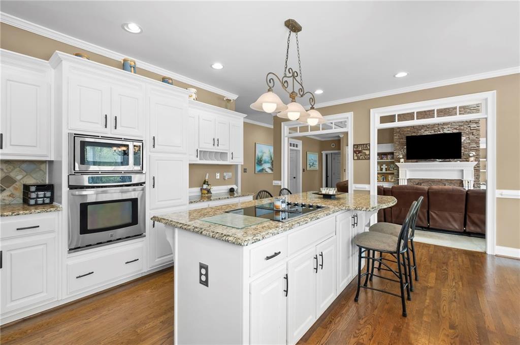 5870 Brookstone Walk Northwest Acworth, GA 30101 - Photo 16 of 79 a open kitchen with stainless steel appliances kitchen island granite countertop a stove top oven a sink dishwasher and white cabinets with wooden floor