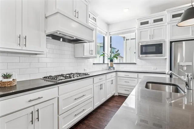 a kitchen with stainless steel appliances granite countertop a sink a stove and refrigerator