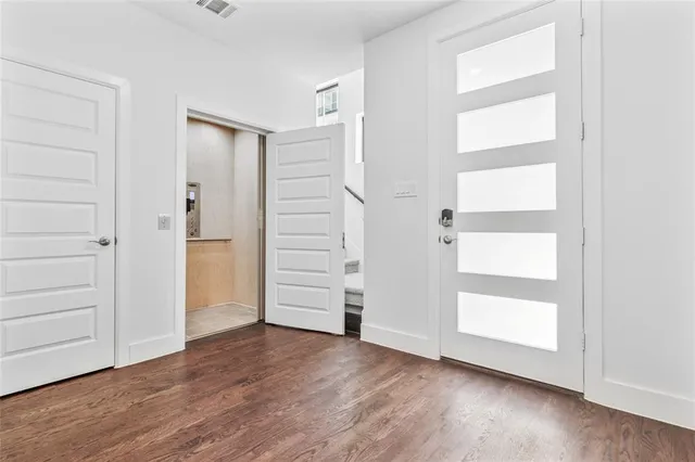 an empty room with wooden floor closet and windows