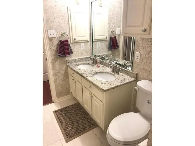 a bathroom with a granite countertop toilet sink and mirror
