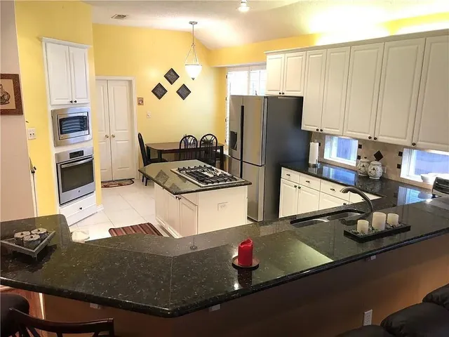 a kitchen with granite countertop a sink stove and refrigerator