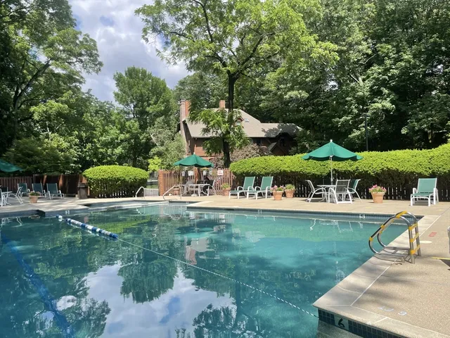a view of a swimming pool and lounge chairs in back yard of the house