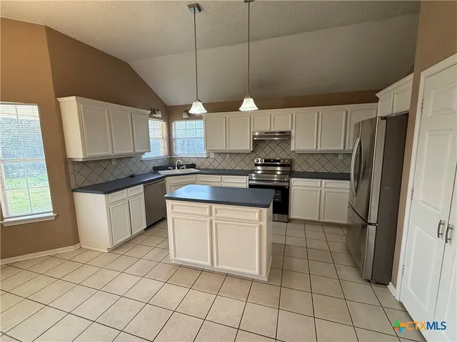 a kitchen with cabinets appliances a sink and a window