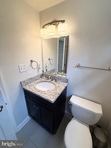 a bathroom with a granite countertop toilet sink and mirror