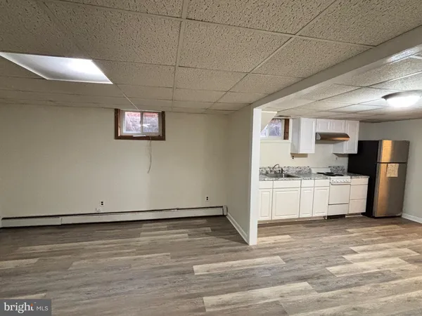 an empty room with wooden floor fireplace and windows