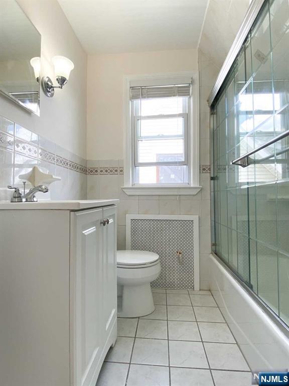 52 Day Street Clifton, NJ 07011 - Photo 11 of 19 a bathroom with a toilet a sink a mirror a window and vanity