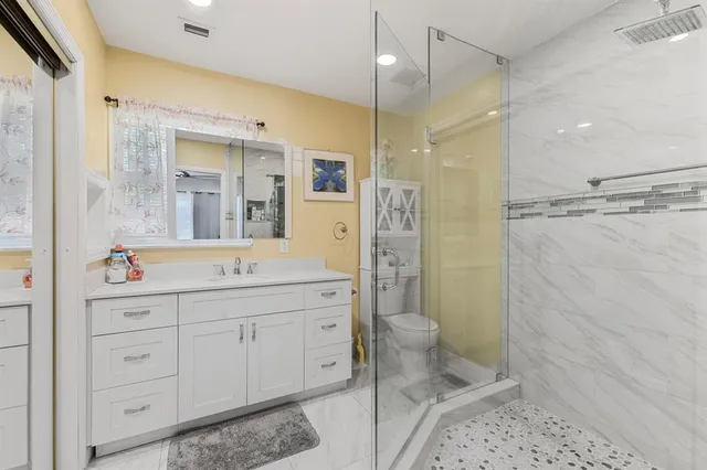 a bathroom with a sink a toilet a mirror and shower