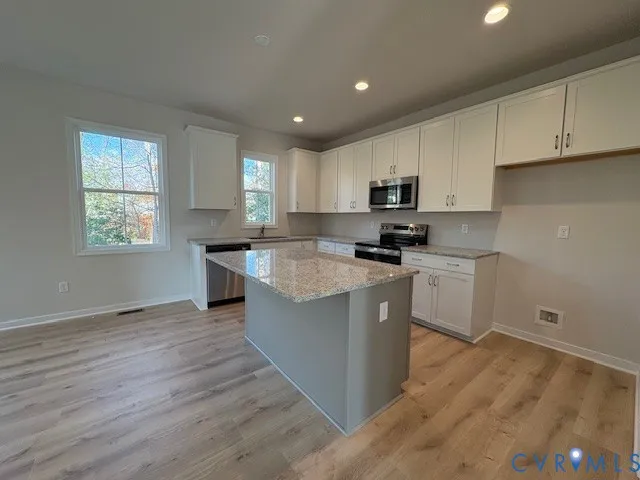a kitchen with granite countertop a sink a counter top space stainless steel appliances and cabinets