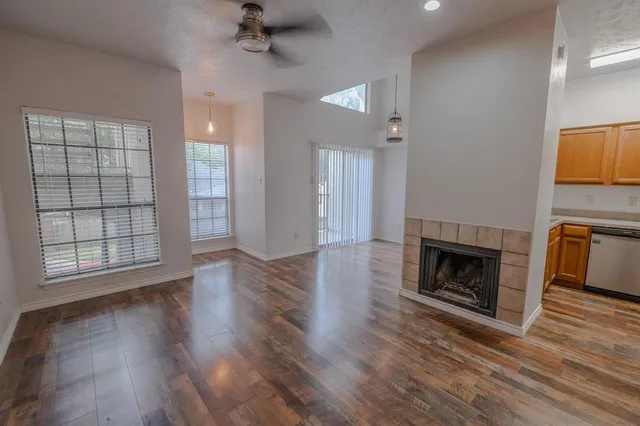 an empty room with wooden floor fireplace and windows