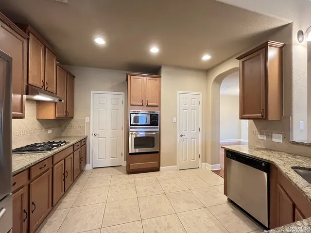 a kitchen with granite countertop a stove top oven and refrigerator