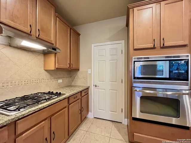 a kitchen with stainless steel appliances granite countertop cabinets and a stove top oven