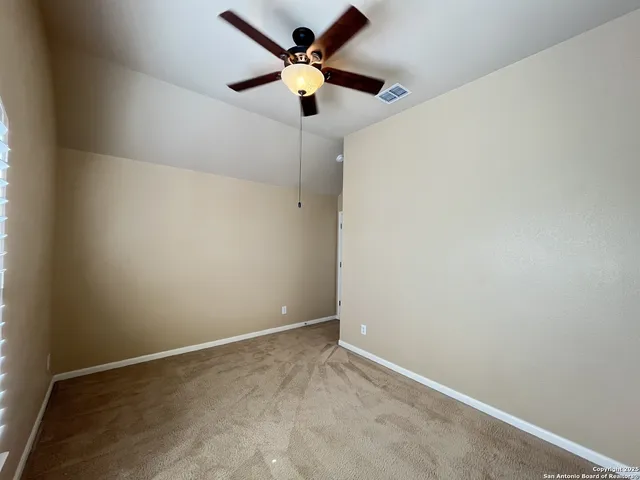 an empty room with a window and a fan