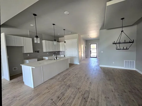 a large kitchen with cabinets wooden floor and a sink