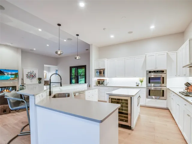a kitchen with kitchen island a stove a sink a oven and a refrigerator