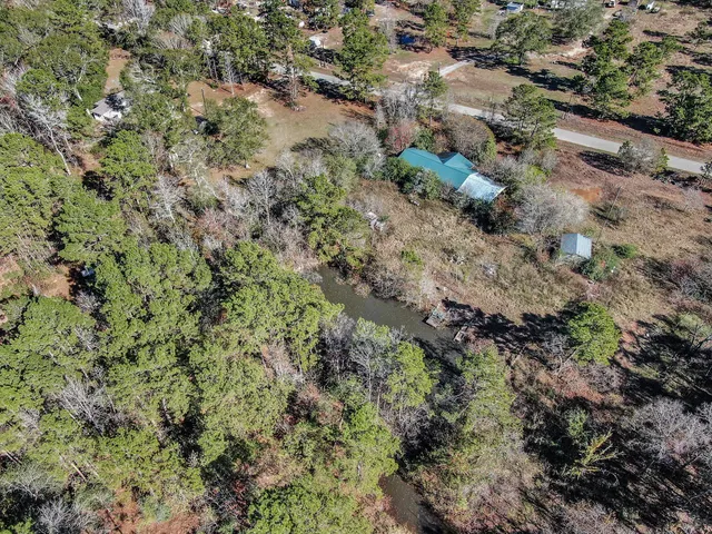 an aerial view of residential house with outdoor space and trees all around
