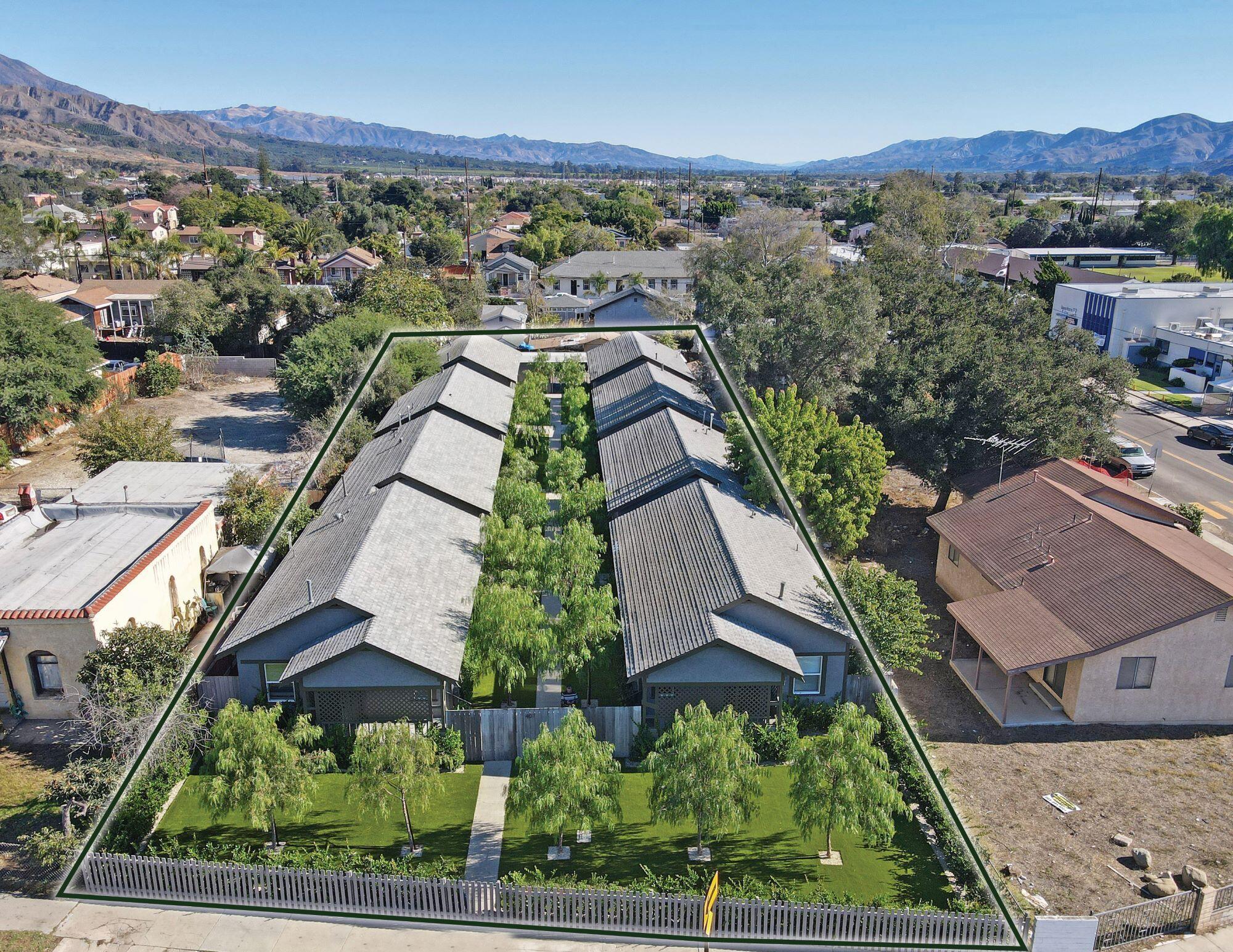 an aerial view of residential houses with outdoor space and parking