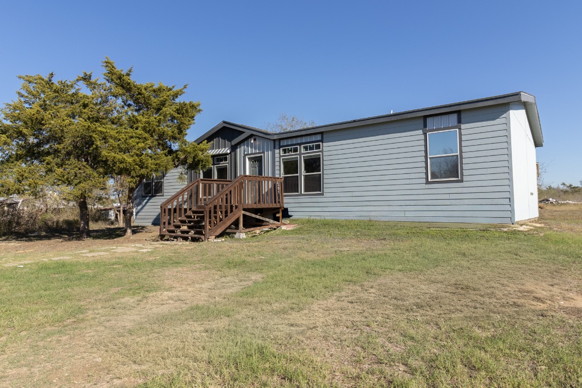 Front view of property with a lawn, board and batten siding, and a wooden deck