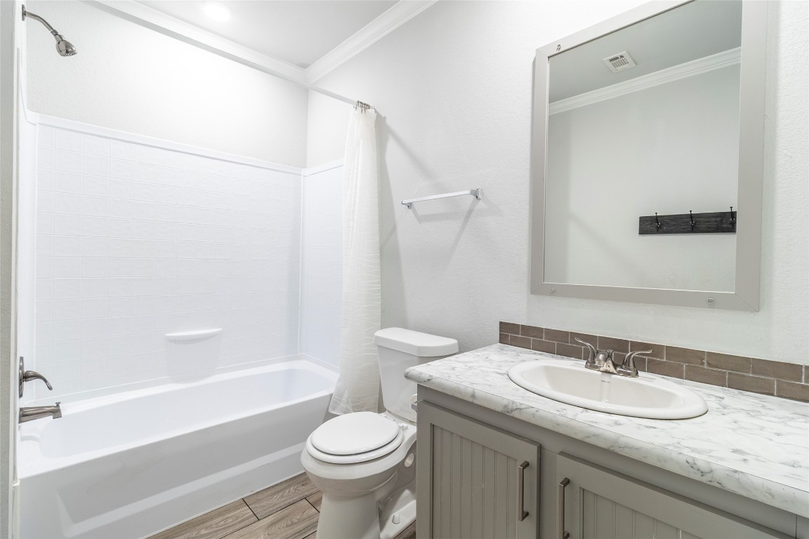 425 High View Ranch Drive Cedar Creek, TX 78612 - Photo 11 of 36 Bathroom featuring vanity, wood finish floors, shower / bath combo, and ornamental molding