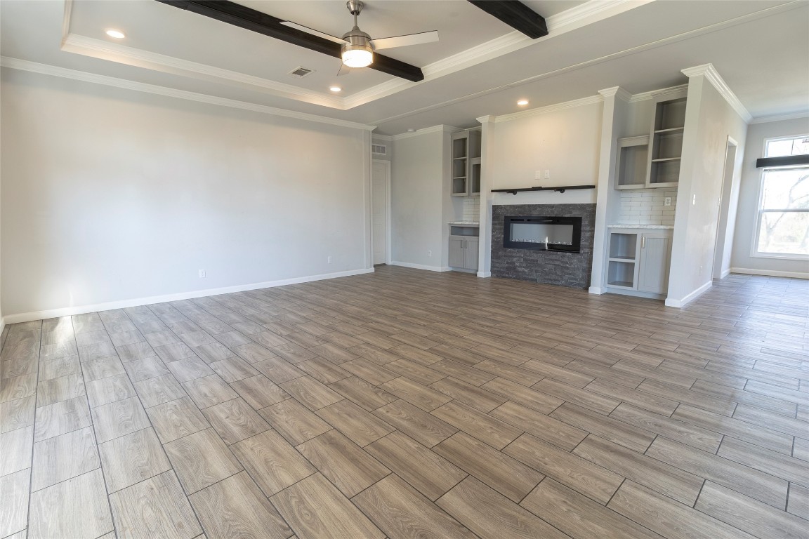 425 High View Ranch Drive Cedar Creek, TX 78612 - Photo 12 of 36 Unfurnished living room featuring wood finish floors, crown molding, a fireplace, ceiling fan, and recessed lighting