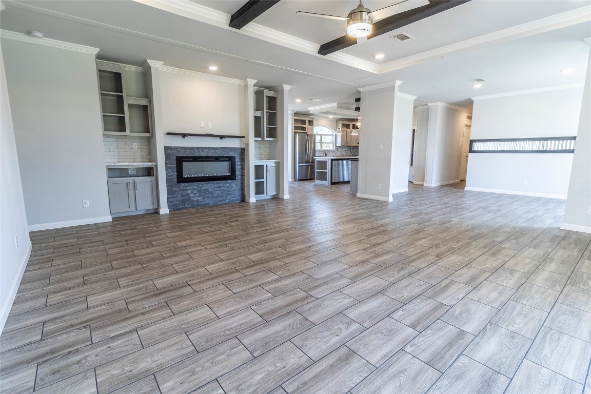 425 High View Ranch Drive Cedar Creek, TX 78612 - Photo 13 of 36 Unfurnished living room featuring ceiling fan, recessed lighting, a stone fireplace, wood tiled floors, and crown molding