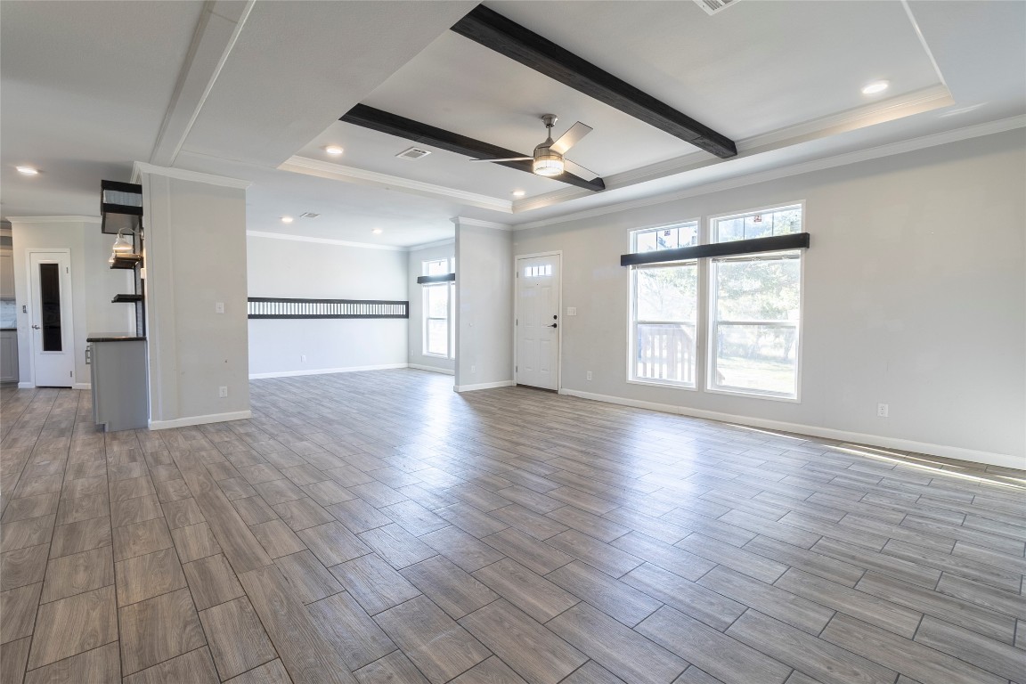 425 High View Ranch Drive Cedar Creek, TX 78612 - Photo 14 of 36 Unfurnished living room with crown molding, a ceiling fan, wood finish floors, beam ceiling, and recessed lighting