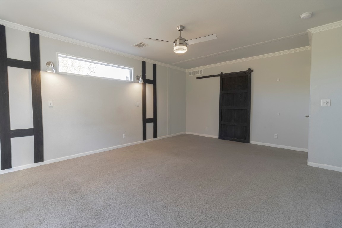425 High View Ranch Drive Cedar Creek, TX 78612 - Photo 21 of 36 Unfurnished bedroom featuring a barn door, crown molding, carpet floors, and a ceiling fan