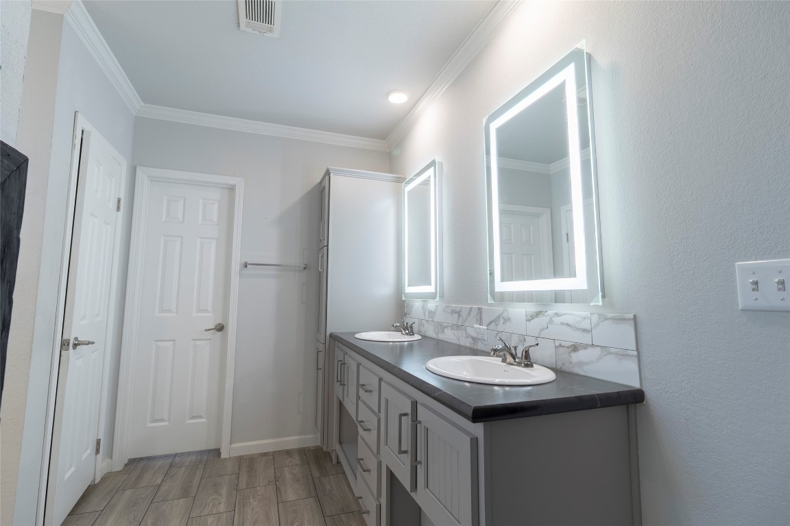 425 High View Ranch Drive Cedar Creek, TX 78612 - Photo 23 of 36 Bathroom with double vanity, backsplash, wood tiled floors, and crown molding